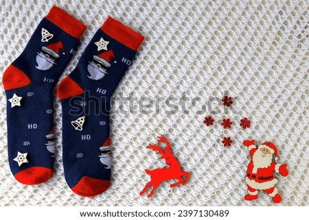 Woolen socks with Christmas pattern, Santa Claus, Saint Nicholas, and New Year s decorations lie on white background. Christmas and New Year holidays concept, gifts background