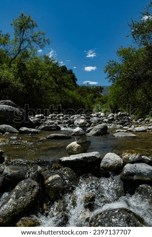 
River with stones and mountains in the background with a clear sky
