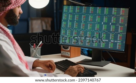 Professional arabic broker investor checking stock exchange valuation, writing down investment financial profit figures. Middle Eastern stockholder looking at market shares graphs on digital device