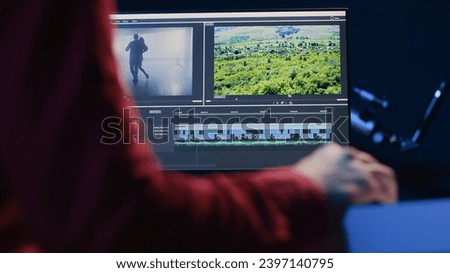Professional video editor editing color grading and lighting in creative office, analyzing film montage, close up shot. Post production videographer manipulates raw footage, handheld camera shot