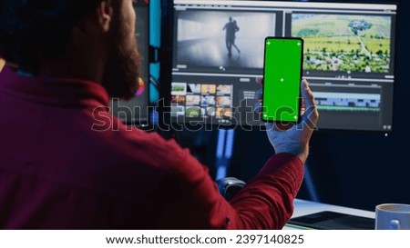 Video editor following tutorial on green screen smartphone, learning to select key frames to use in movie montage. Freelancing applying editing techniques seen online on chroma key phone