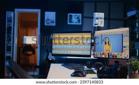 Creative office desk with multi monitor computer setup used for image retouching, zoom in shot. Empty blue neon lit specialized post processing studio with editing software interface on PC screens