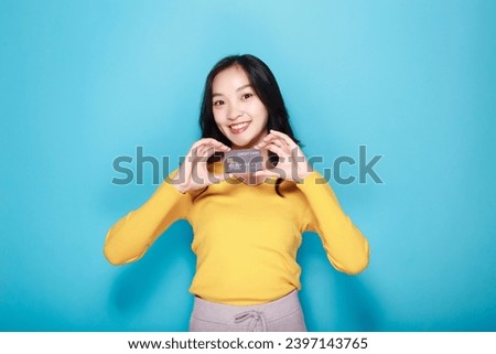 Asian woman posing with a credit card, Portrait of a beautiful young woman in a light blue background, happy and smile, posting in stand position.