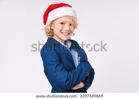 Successful young school boy in Santa`s hat ready for Christmas isolated over white background