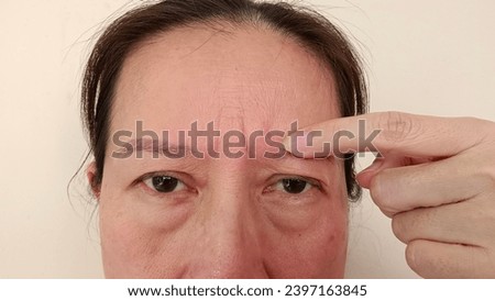 A middle-aged woman has wrinkles on her forehead. Royalty-Free Stock Photo #2397163845