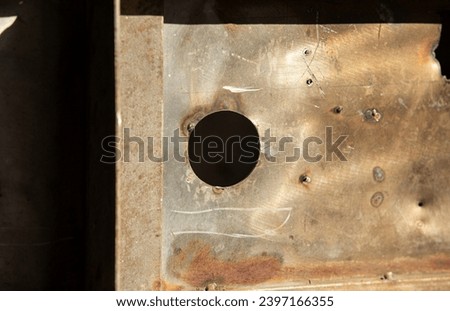Close-up of a rusty metal door with a hole in it