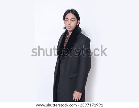 portrait of handsome male wearing black coat , leopard print shirt posing on white background