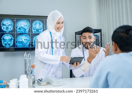 Muslim male and female doctors in medical uniforms was sitting at the patient's examination table and was examining and talking about the patient with a smiling and worried face in hospital.