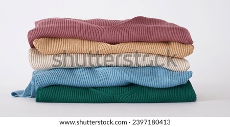 stack of knitted, winter and autumn colorful folded women's clothes on white background. can be used for autumn and winter concept showcasing clothing items. copy space, close up, top view.