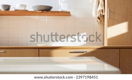 A sunny kitchen with white tile walls, a wooden table and sink. Royalty-Free Stock Photo #2397198451