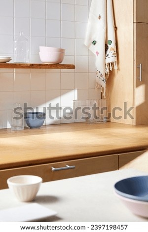 A sunny kitchen with white tile walls, a wooden table and sink. Royalty-Free Stock Photo #2397198457