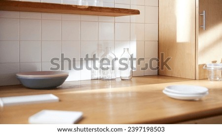 A sunny kitchen with white tile walls, a wooden table and sink. Royalty-Free Stock Photo #2397198503
