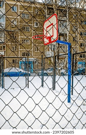 An empty snow-covered basketball court on a winter day