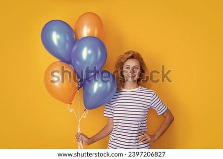 positive woman hold party balloons in studio. woman with balloon for party isolated on yellow