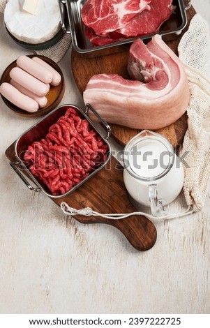 Saturated fats on tables. Raw meat, sausages, cheese, butter. Bad food concept. Top view, copy space. Royalty-Free Stock Photo #2397222725