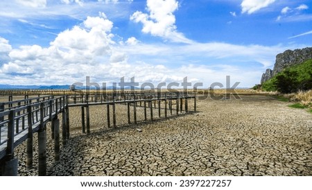 Wood walk way at Sam Roi Yot Freshwater Marsh or Bueng Bua Khao Sam Roi Yot National Park in Thailand. Boardwalk bridge. In Summer the ground is dry and cracked, there is no water in the pond. Royalty-Free Stock Photo #2397227257