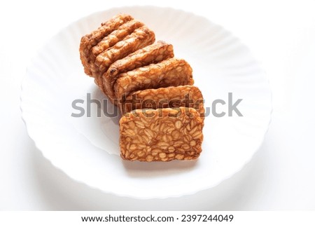 Fried tempeh is served on a white ceramic plate