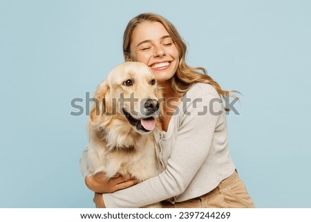 Young smiling happy cheerful owner woman with her best friend retriever wear casual clothes cuddle hug dog close eyes isolated on plain pastel light blue background studio. Take care about pet concept Royalty-Free Stock Photo #2397244269