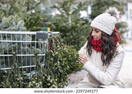 A young woman looks at mistletoe at the market during Advent.
