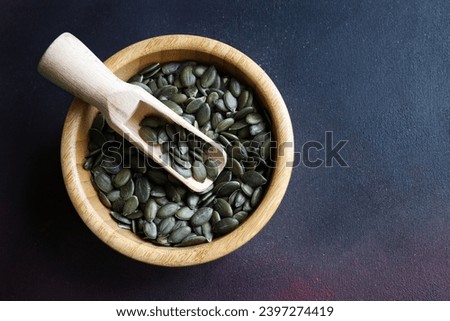 Natural green pumpkin seeds without shell isolated on dark background. Healthy food concept. Overhead view. Copy space. Royalty-Free Stock Photo #2397274419