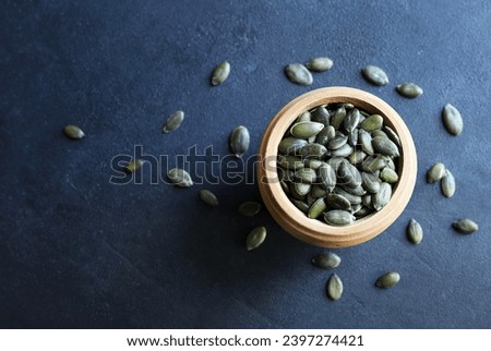 Natural green pumpkin seeds without shell isolated on dark background. Healthy food concept. Overhead view. Copy space. Royalty-Free Stock Photo #2397274421