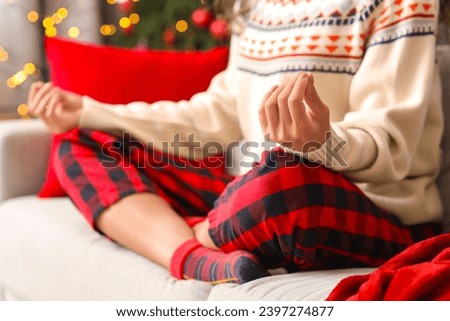 Beautiful young African-American woman meditating on sofa in room decorated for Christmas, closeup
