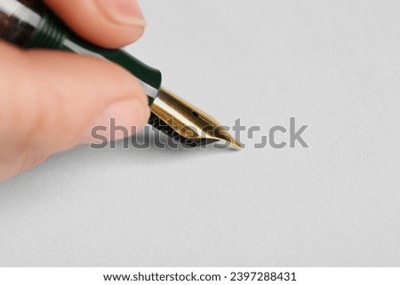 Woman with fountain pen above white paper, closeup. Space for text