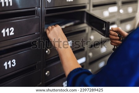Woman checking mailbox in apartment building. Royalty-Free Stock Photo #2397289425