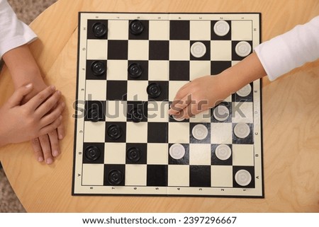 Children playing checkers at coffee table, top view
