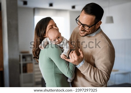 Portrait of young happy man and woman holding newborn cute babe dressed in white unisex clothing. Royalty-Free Stock Photo #2397297325
