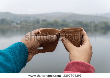 couple enjoying hot tea served in traditional pottery clay cup with blurred mountain lake landscape