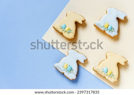 Easter homemade baked gingerbread with different pattern of icing or cookies in the shape of bunny. Blue and yellow background, top view, copy space	