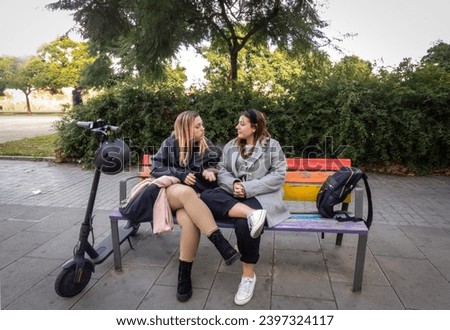 two young girls sitting on a bench chatting animatedly