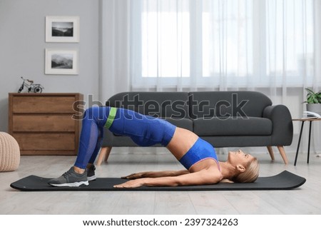 Athletic woman doing exercise with fitness elastic band on mat at home Royalty-Free Stock Photo #2397324263