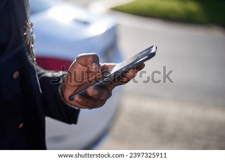 Cropped image of Black business man holding cellphone while outside Royalty-Free Stock Photo #2397325911