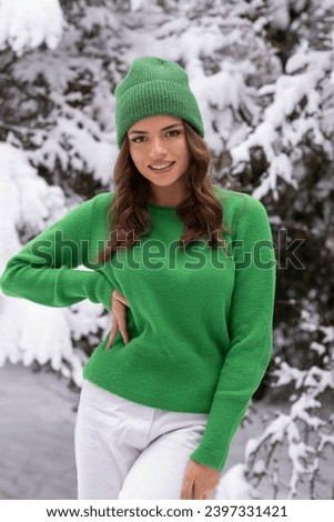 Beautiful brunette in green hat in snowy forest.