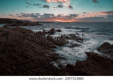 Long exposure photography at sunset of the rough sea of Li Cuncheddi, Sardinia, Olbia. The harmonious colors at sunset contrast with the pathos of the storm.