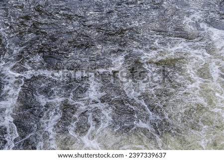 Close up detail of fierce white water river rapids from a clean deep green colored river forming a textured background.