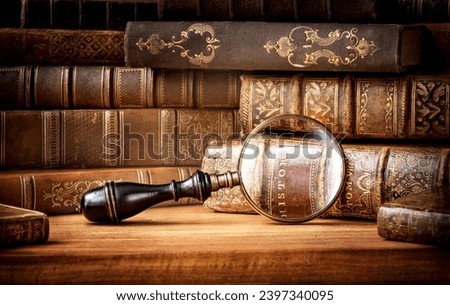 Old books and antique magnifying glass on a wooden background. An ancient book and magnifying glass as a symbol of history, education. Old book history background.