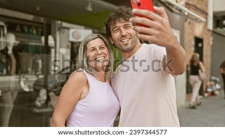 Joyful mother and son capture their happy moments together, making a cool selfie in the city street with their smartphone, their smiles radiating positivity and the love shared between them.