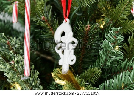 A candy cane shaped ornament hung on the Christmas tree.