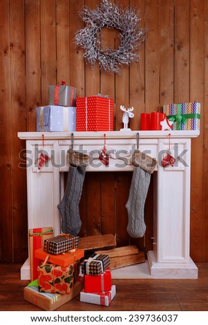 Fireplace with gifts and Christmas decoration on wooden wall background