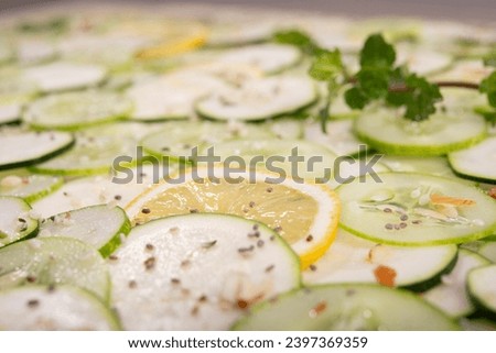 Close up view of sliced lemon amidst many cucumbers.