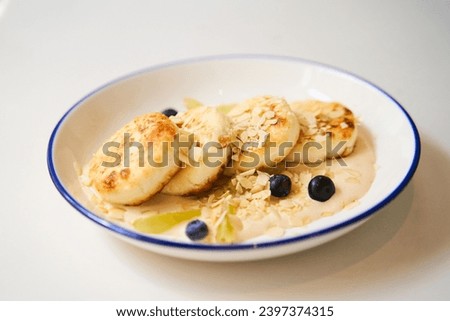 Close-up photo of round cheesecakes on a plate with sauce and blueberries.