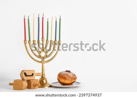 Menorah with dreidels and tasty donut isolated on white background. Hanukkah celebration