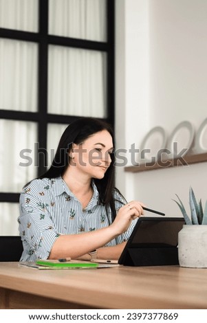 In the office, a young brunette girl is working on a tablet