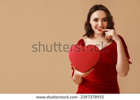 Happy young woman with gift box on brown background