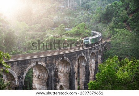 Blue train goes through jungle. Nine arch bridge, Demodara, Sri Lanka. Old bridge in Ceylon. Nine Arches Bridge from above, Sri Lanka. High quality photo Royalty-Free Stock Photo #2397379651