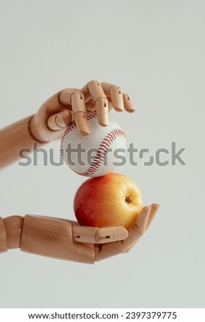 Wooden hands hold a baseball and a ripe apple. The concept of combining sports and healthy food.