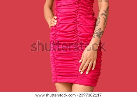 Young woman with tattooed arm on pink background, closeup